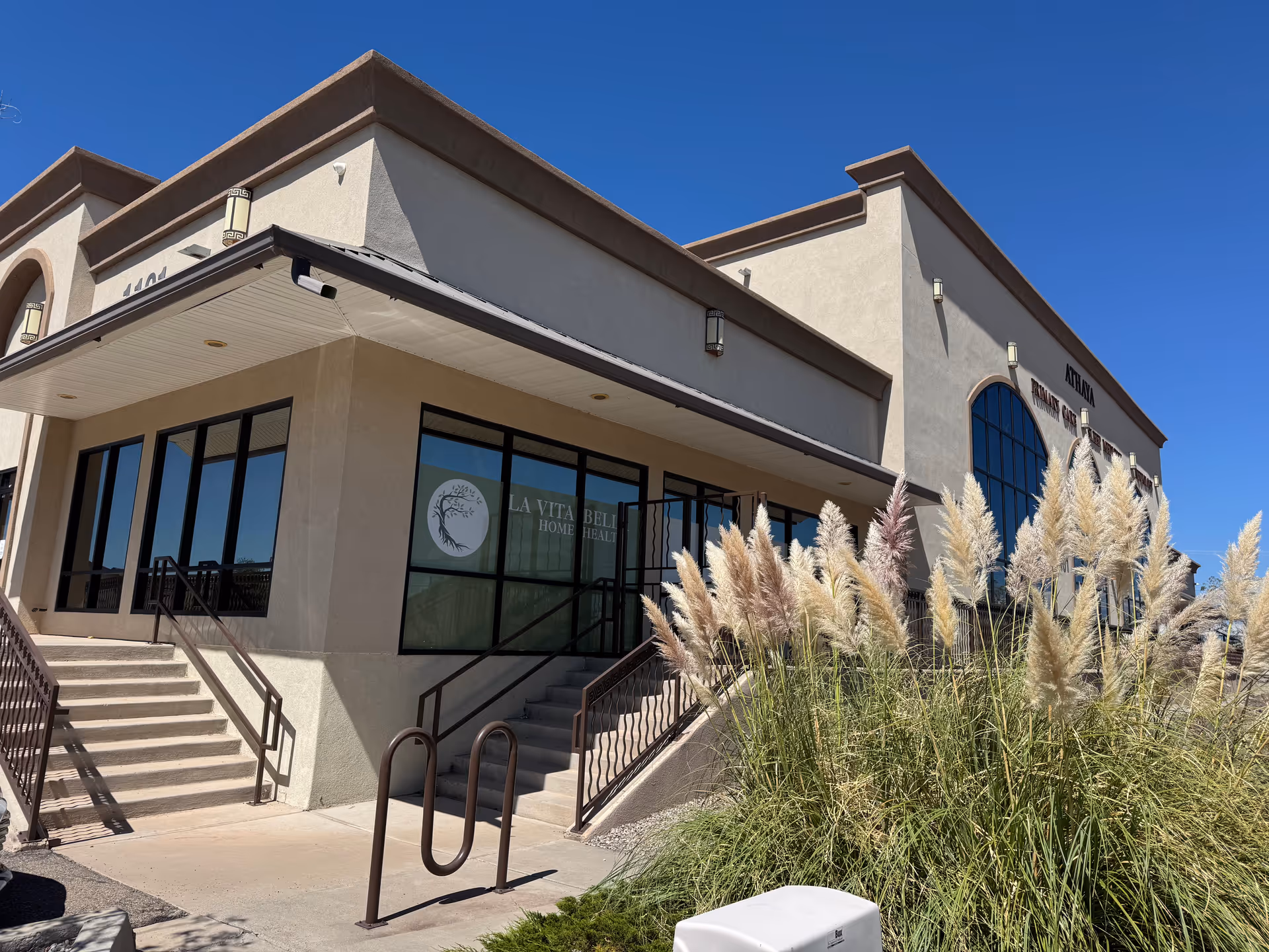 Exterior view of La Vita Bella Home Health Care building with stairs and tall grasses.