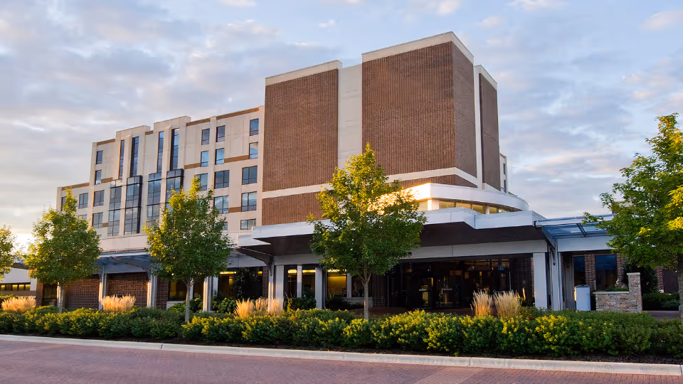 Exterior view of a modern brick-and-beige facade building with a landscaped entrance.