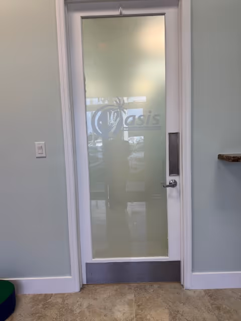Frosted glass door with Oasis logo in a light green interior hallway.