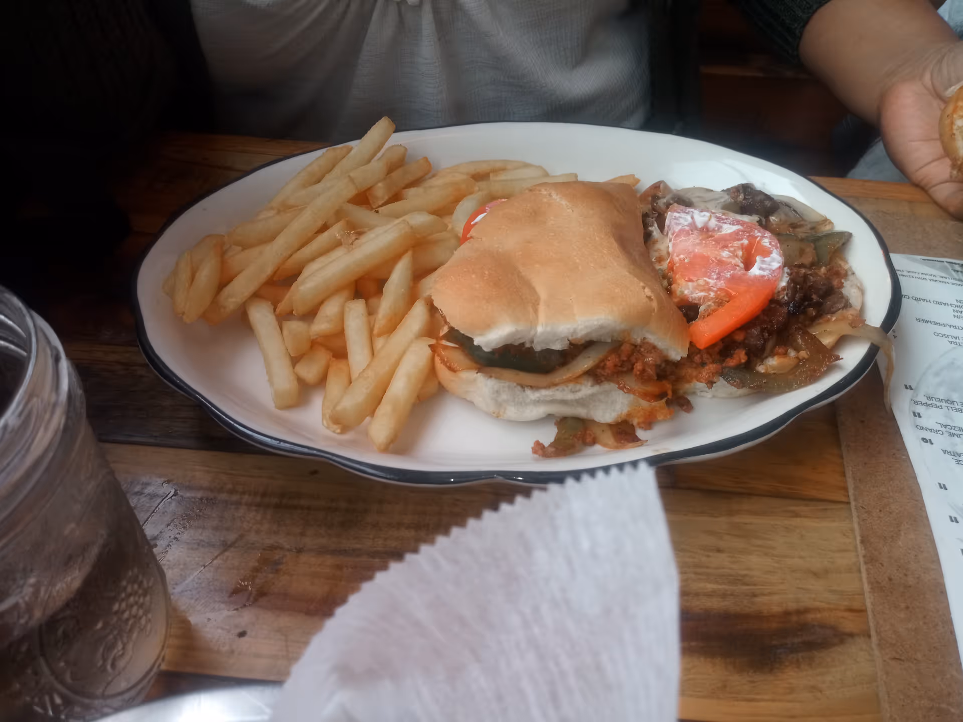 Burger and fries on a plate at a wooden dining table.