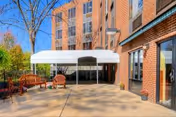 Brick exterior of Green Meadows with a white canopy over a paved patio and wooden seating.