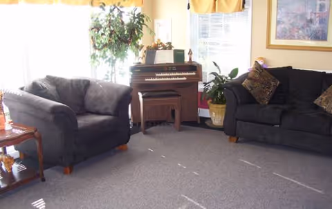 Cozy living room in Clemmons Village II Assisted Living with two sofas and a piano.
