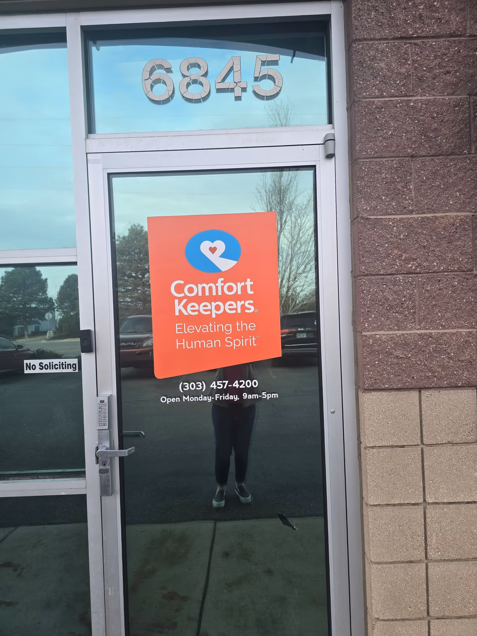Glass entry door with Comfort Keepers sign and the number 6845 above.