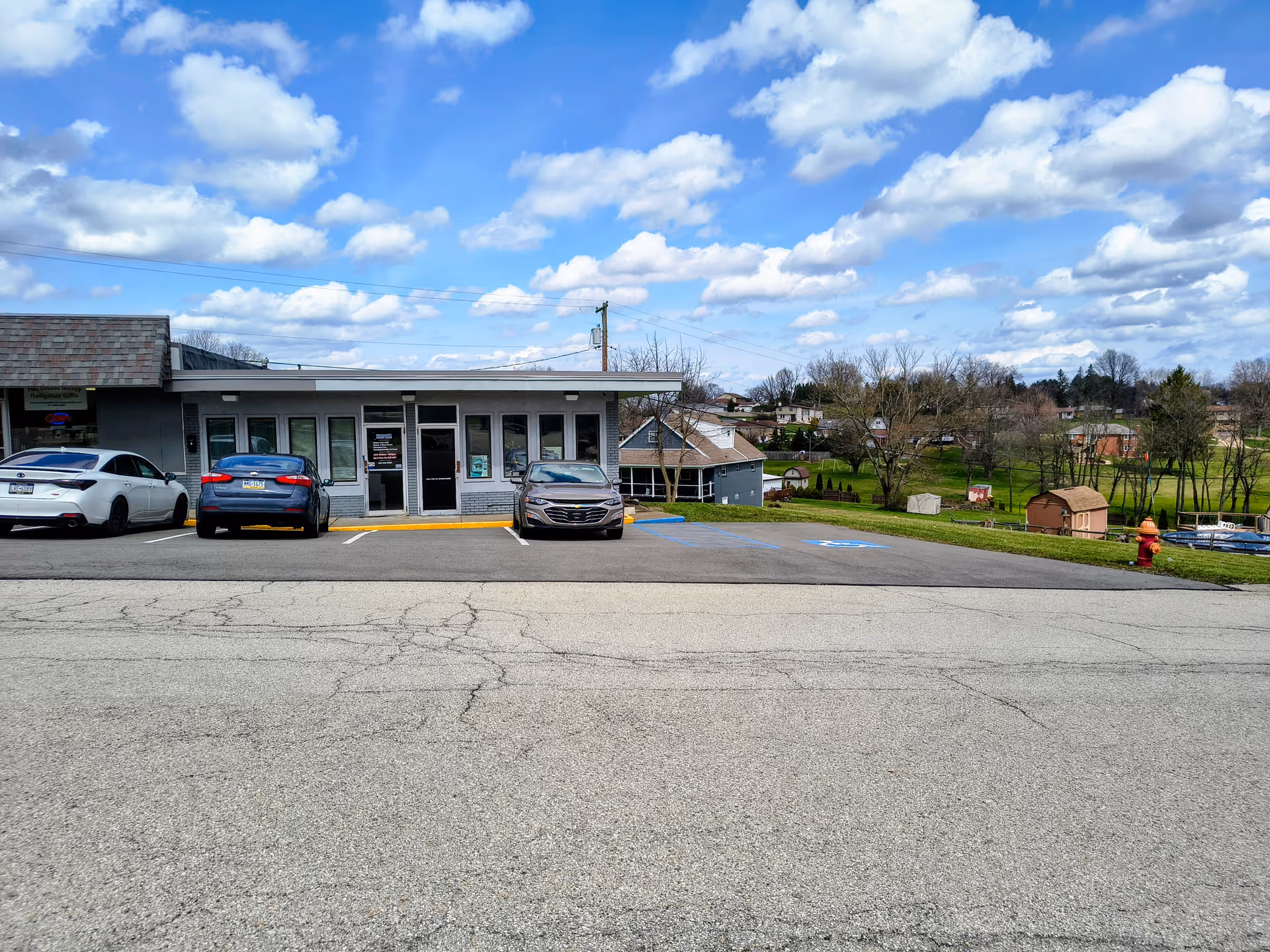 Front of a single-story building with a parking lot and landscaped surroundings.