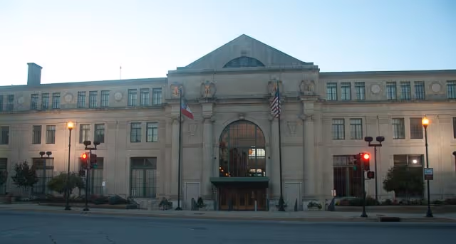 Classical stone building facade with central arched entrance and flags
