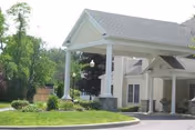 Front exterior view of a care home with a covered entrance and lawn.