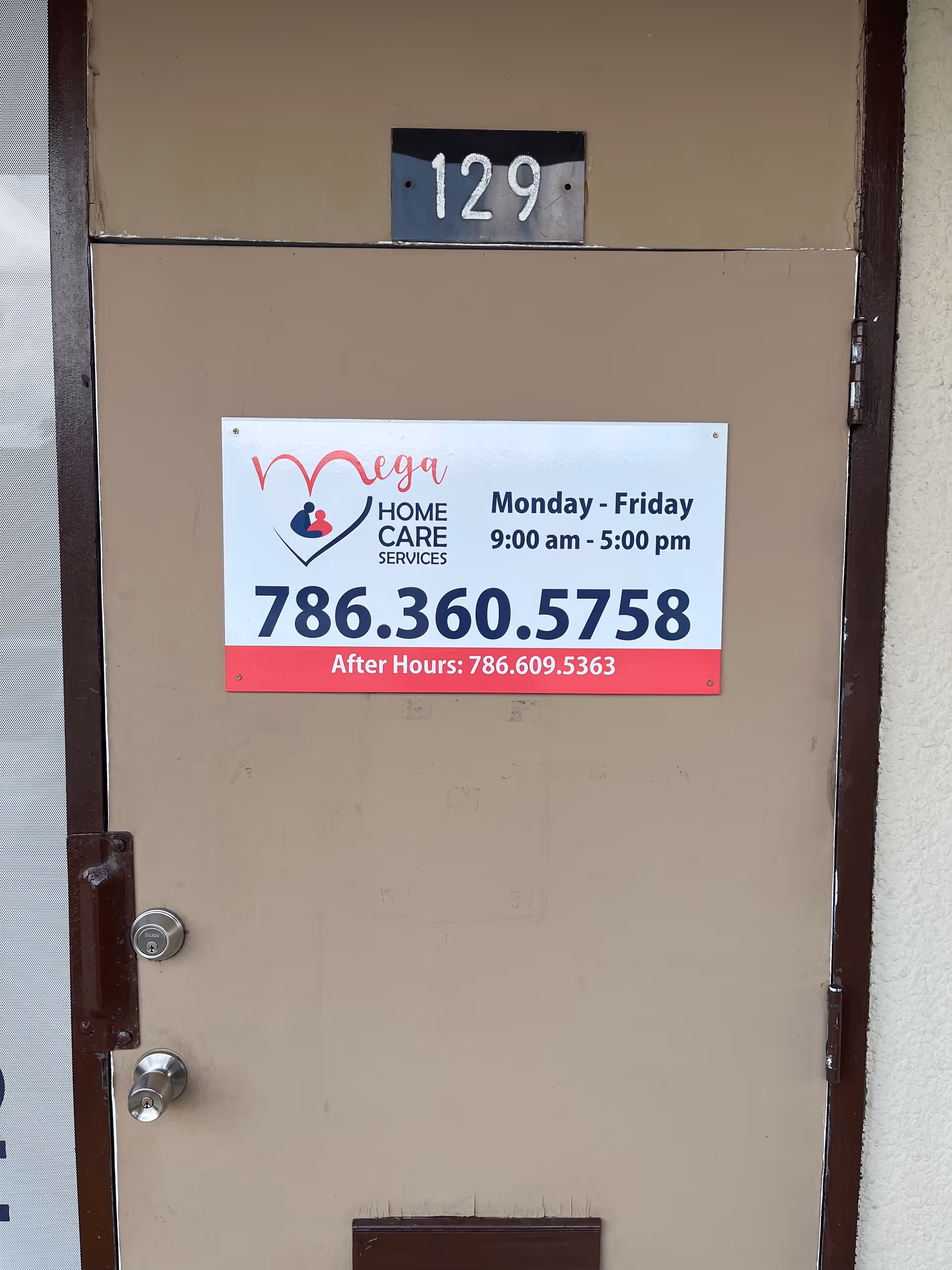 Brown entrance door displaying Mega Home Care Services sign and number 129