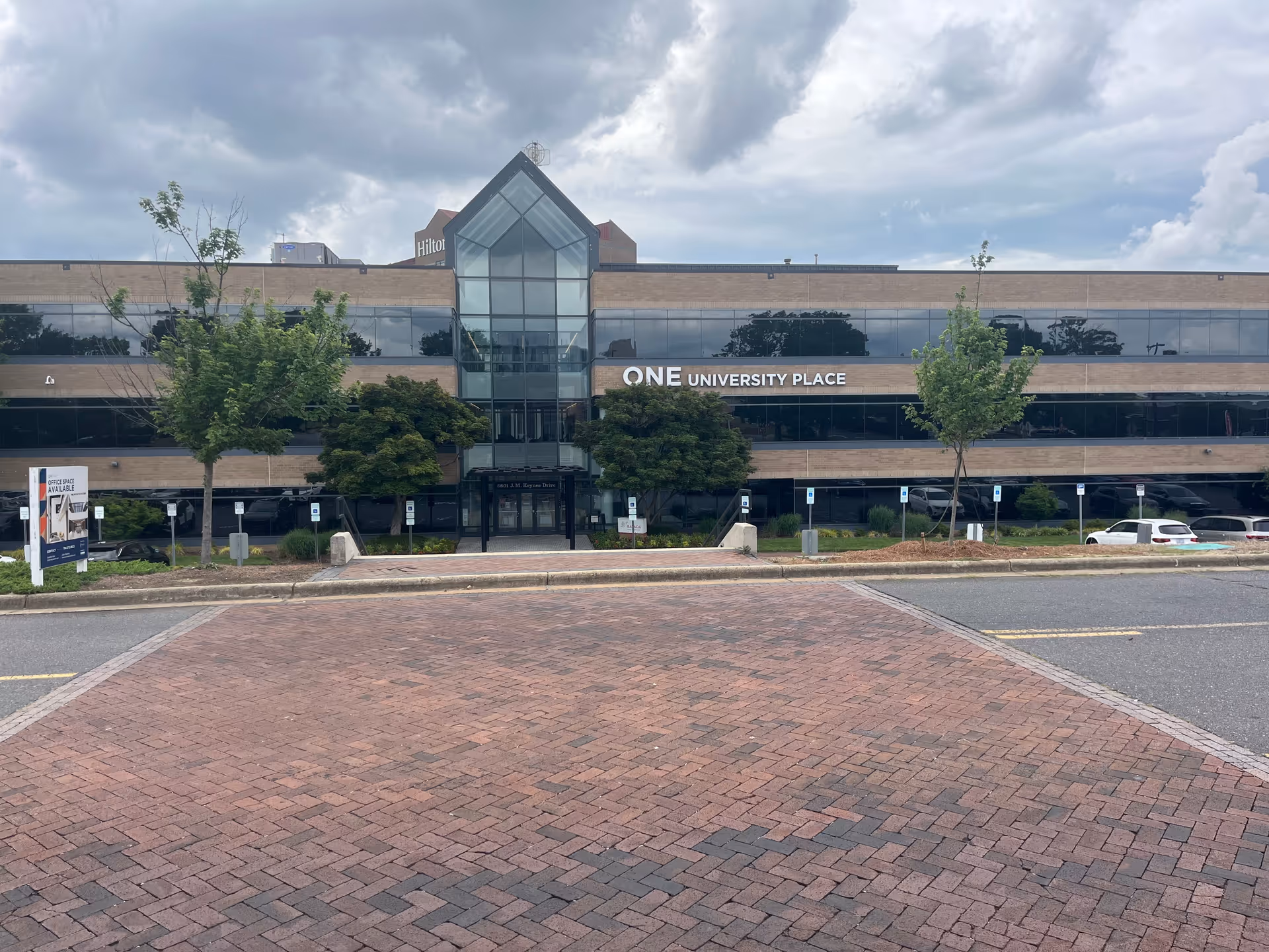 Front view of a brick-and-glass office building with a central glass atrium.