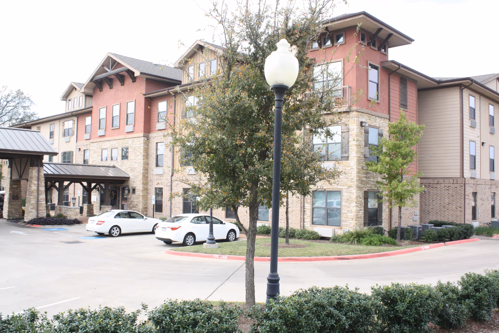 Exterior view of Isle at Watercrest Bryan with parked cars and landscaping.