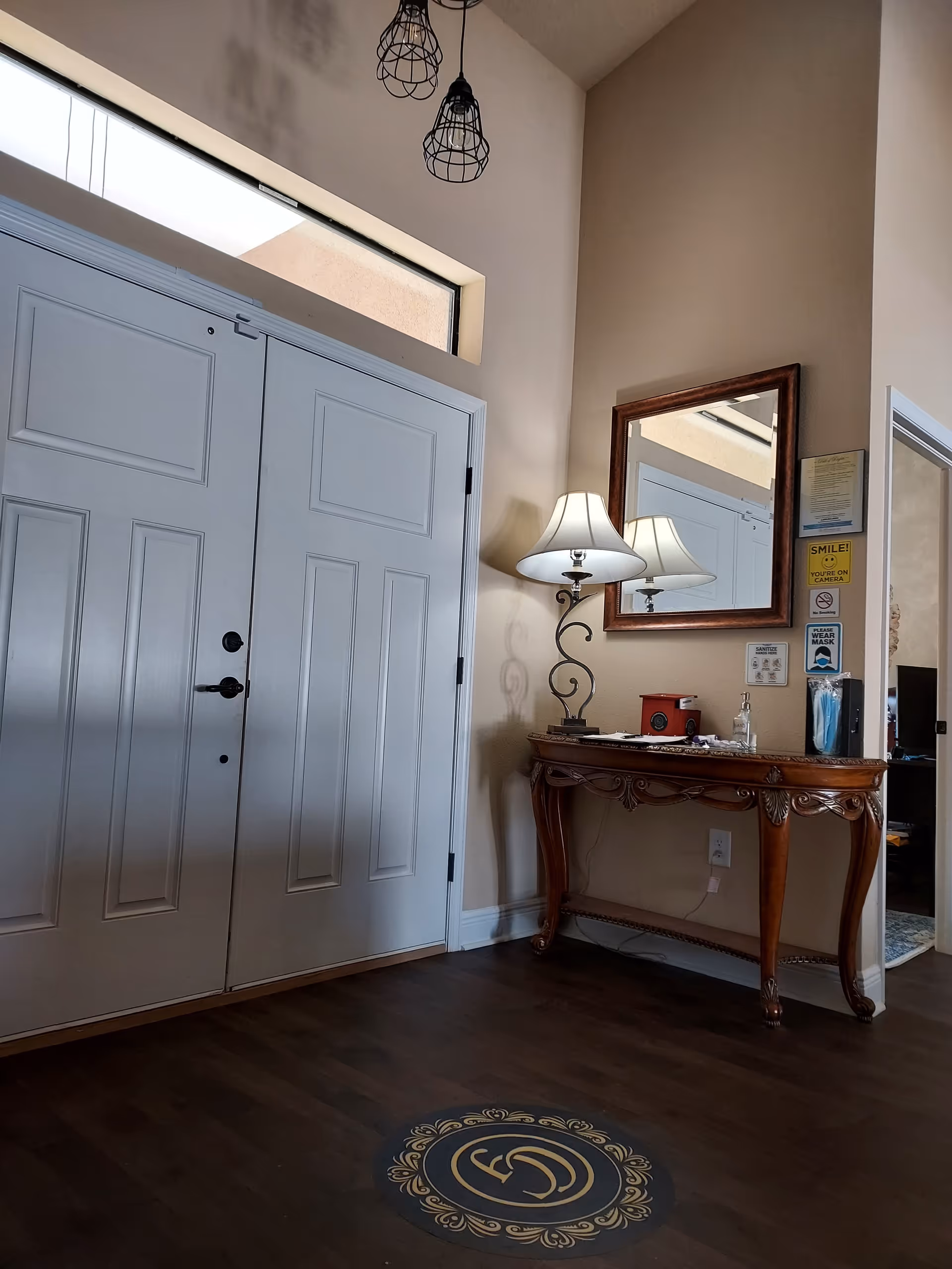Elegant foyer with double doors, console table, lamps, and mirror in a residential lobby.
