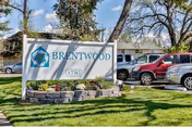 Brentwood Post-Acute facility sign with landscaping and parked cars in front.