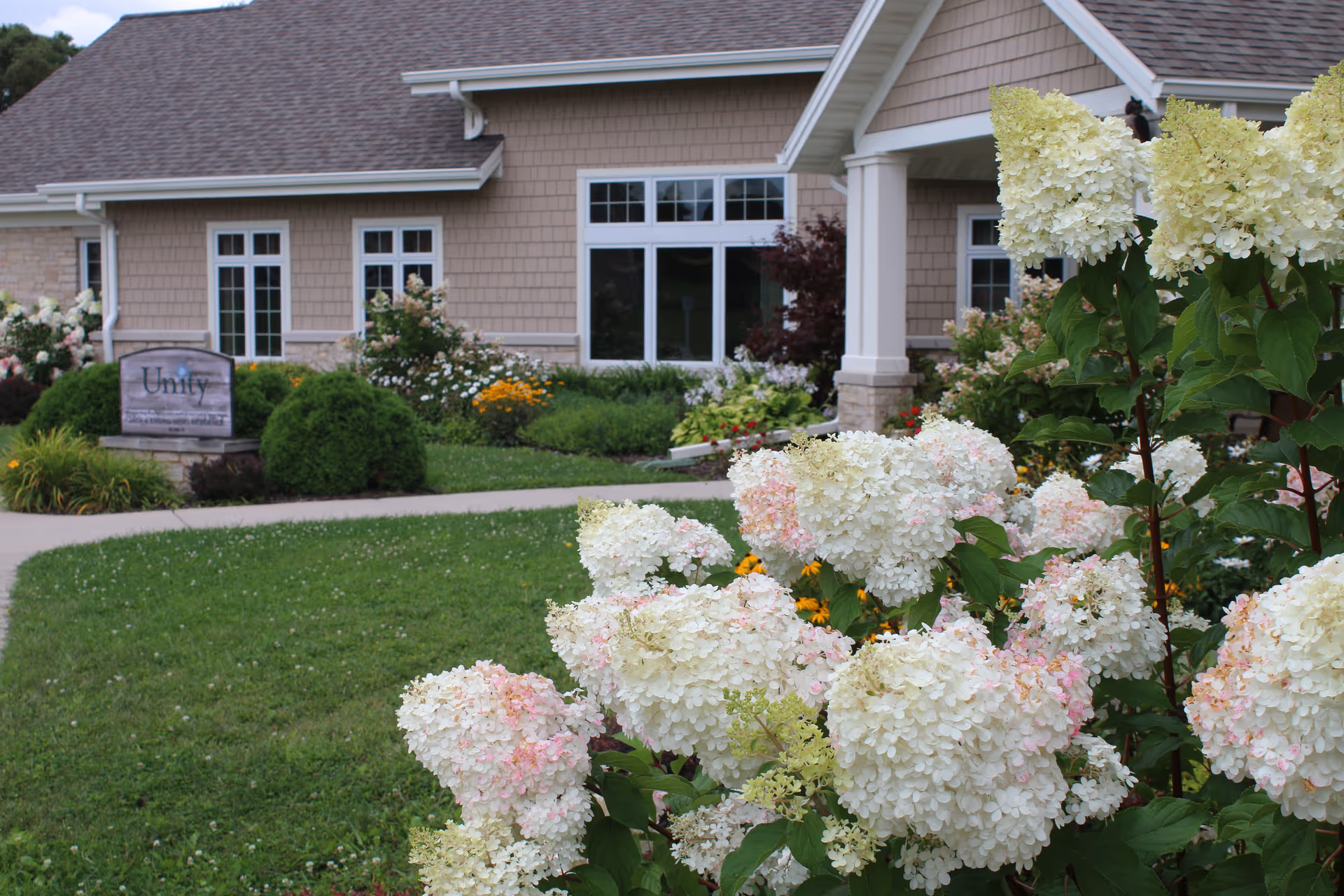Front view of Unity Hospice building with landscaped garden and white hydrangeas.