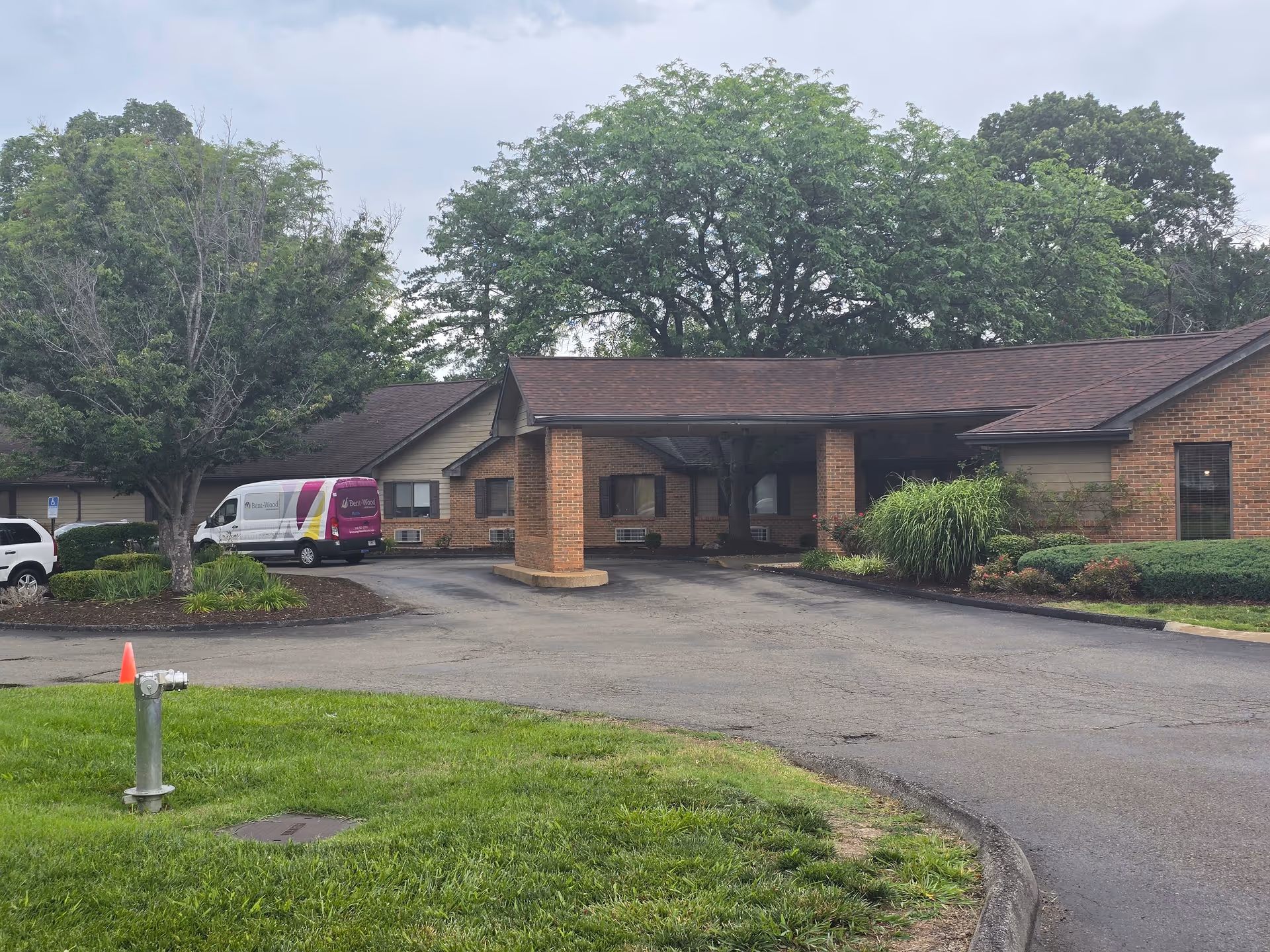 Exterior view of a brick nursing and rehabilitation center with a front entrance canopy and driveway.