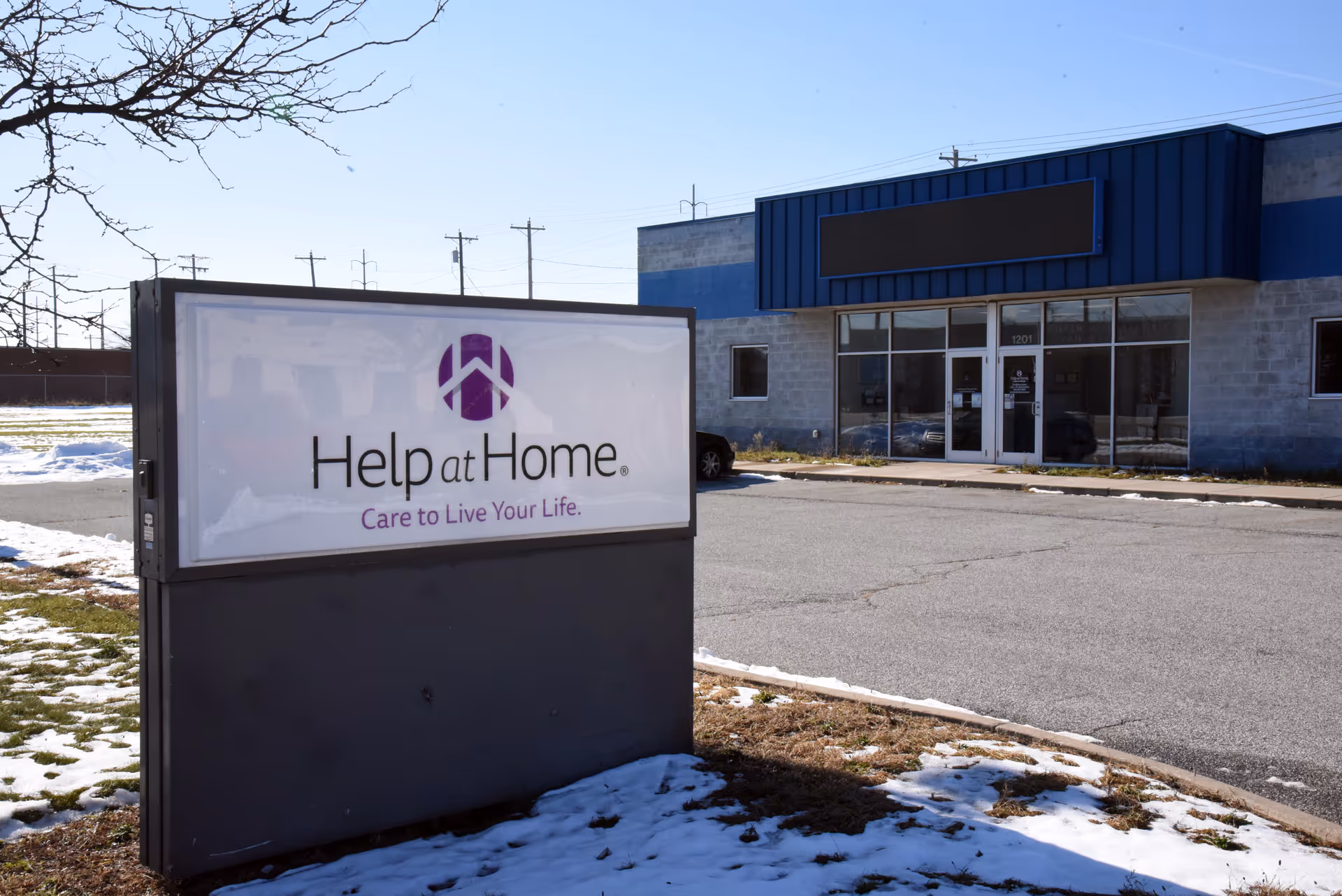 Exterior view of a Help at Home facility with a large sign in the foreground.