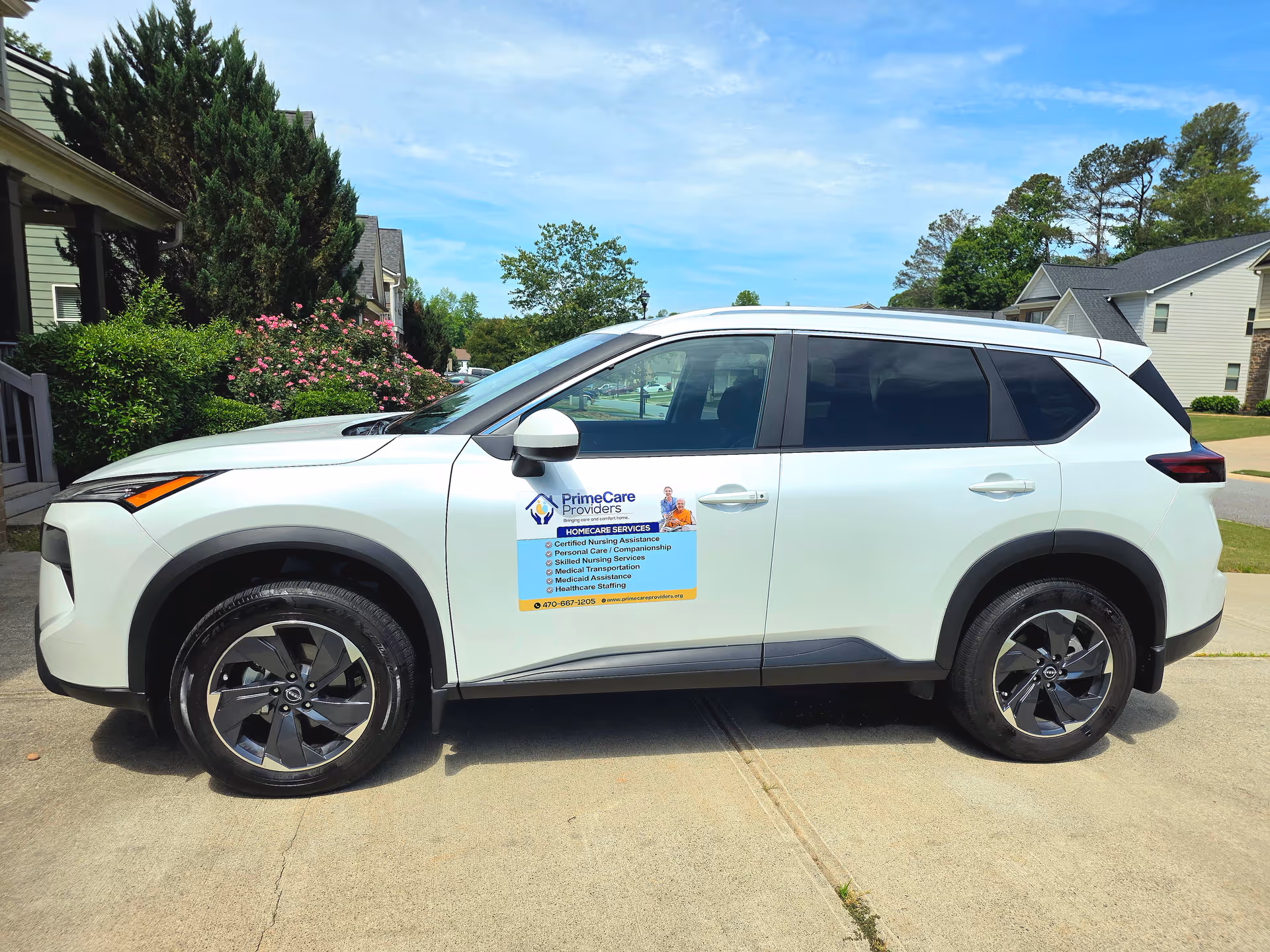 White SUV with PrimeCare Providers LLC logo parked on a driveway beside suburban homes.
