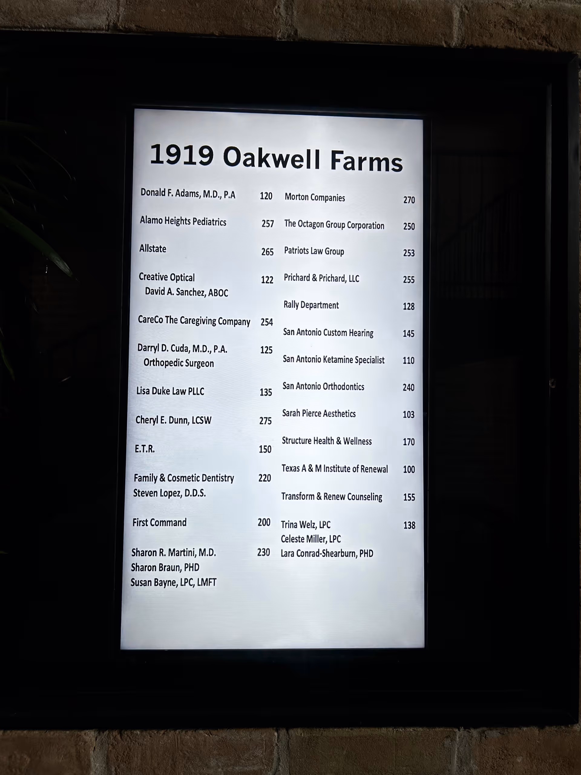 Exterior signboard showing '1919 Oakwell Farms' directory with tenant names.