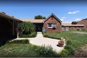 Long Hollow Terrace front entrance with walkway, lawn, and shrubs under a blue sky.