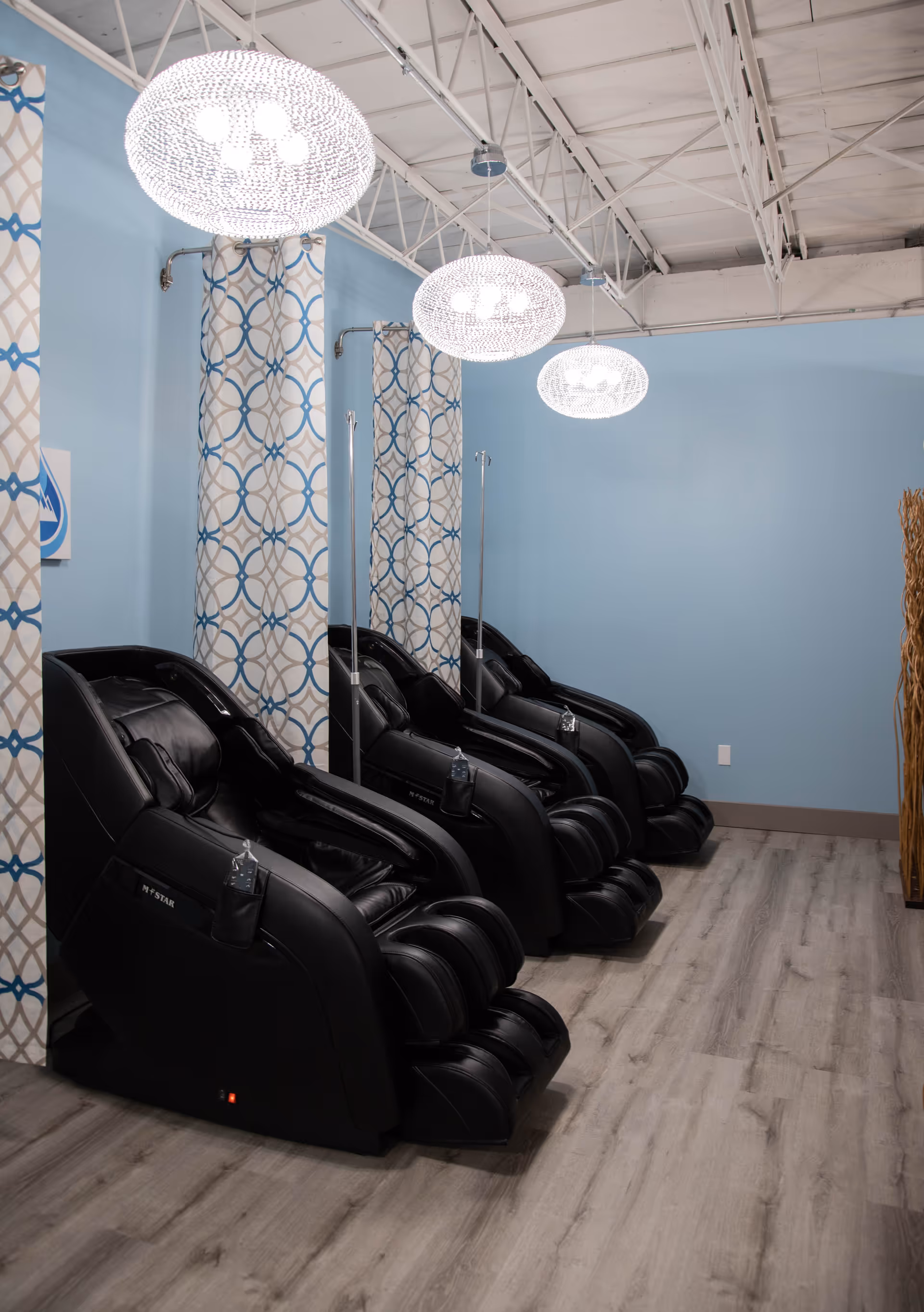 Row of black massage chairs along blue walls in a wellness center treatment room.
