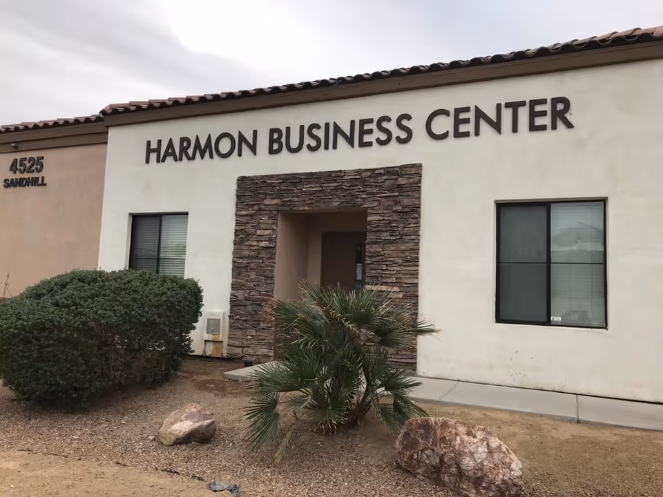 Front of a beige building with Harmon Business Center sign and entrance.