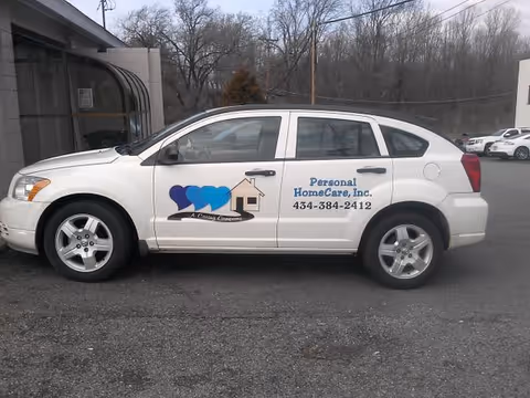 White sedan with Personal HomeCare, Inc. branding parked outside a building.