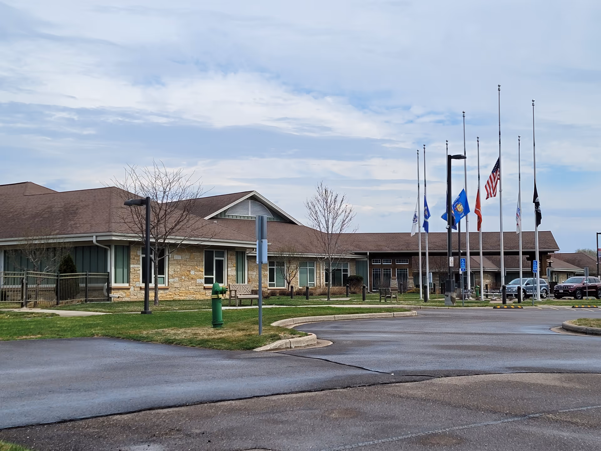 Front view of Wisconsin Veterans Home at Chippewa Falls with flagpoles and parking.