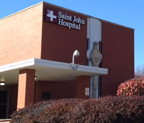 Exterior view of Saint John Hospital with brick facade and white canopy entrance.