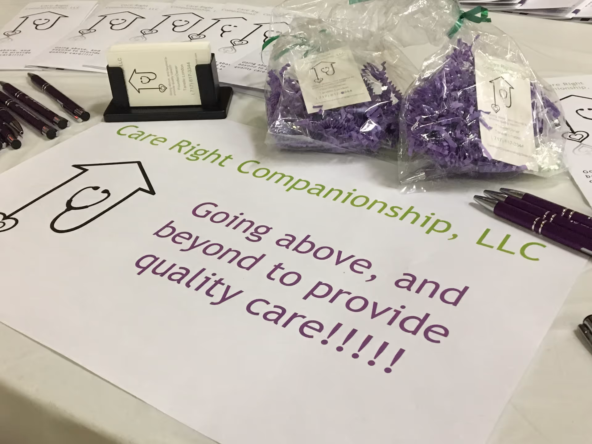 Promotional table setup featuring Care Right Companionship branding and purple gift bags.