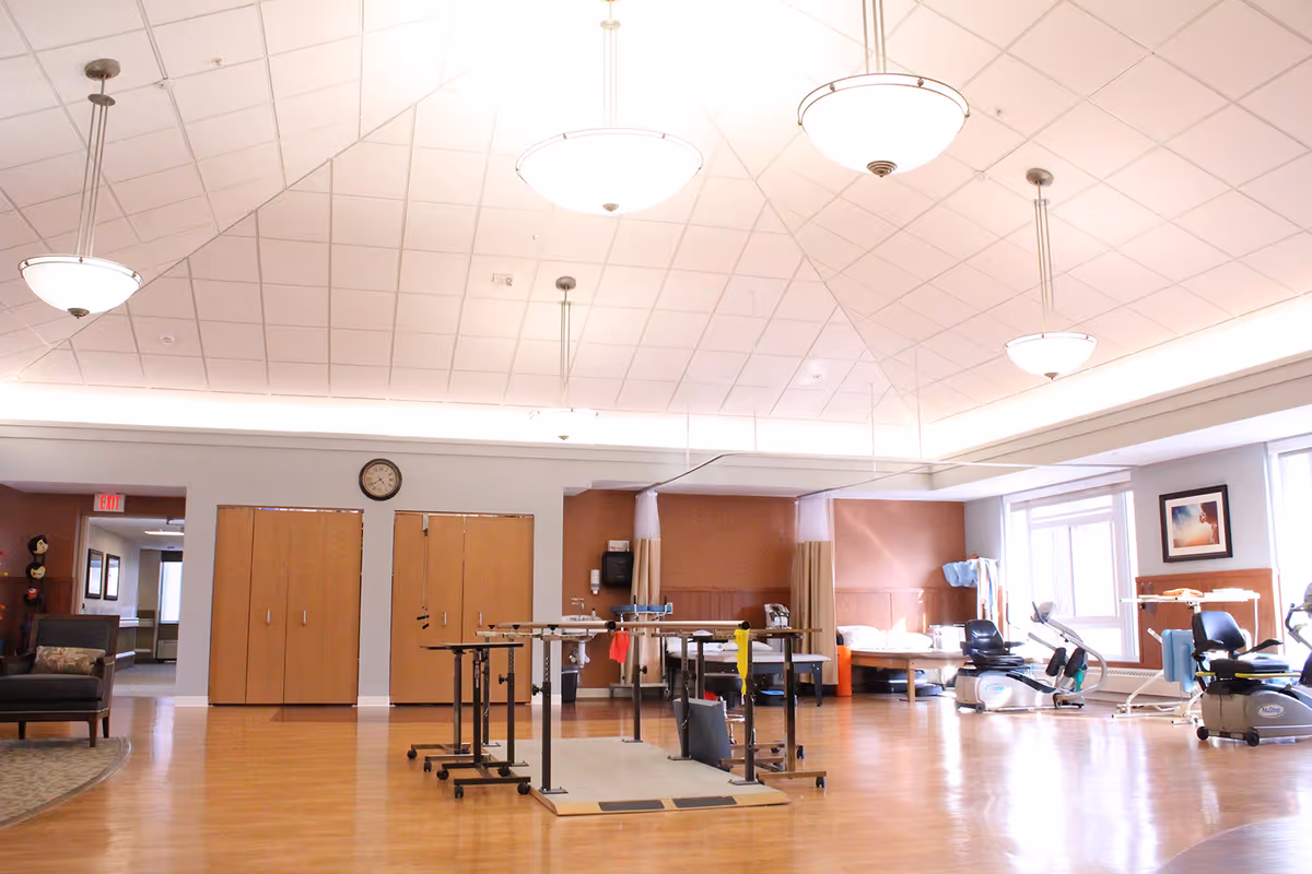 Spacious interior rehab gym in a senior facility with exercise equipment and therapy beds.