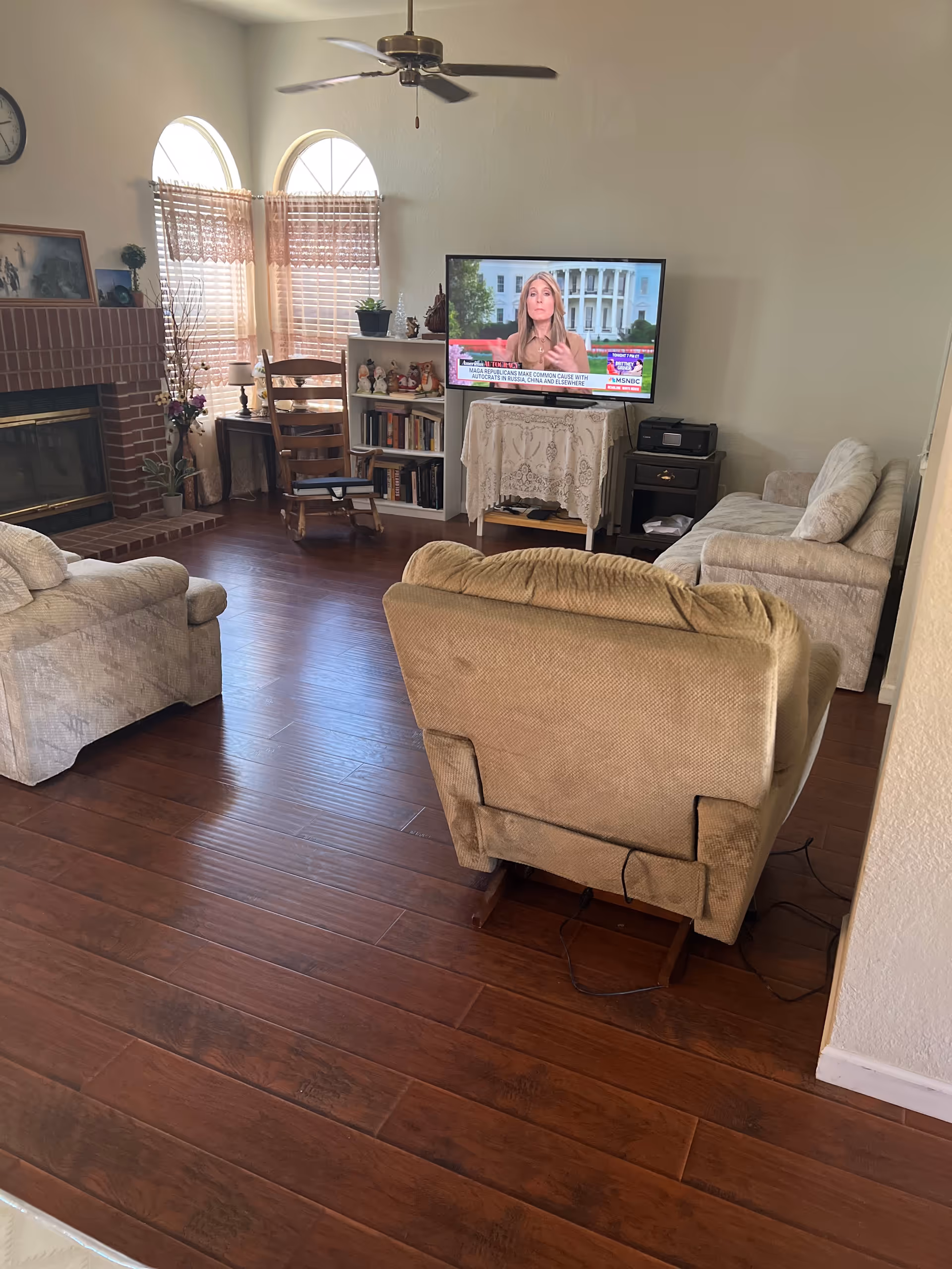 Cozy living room with beige furniture, wood floors, a fireplace, and a TV.