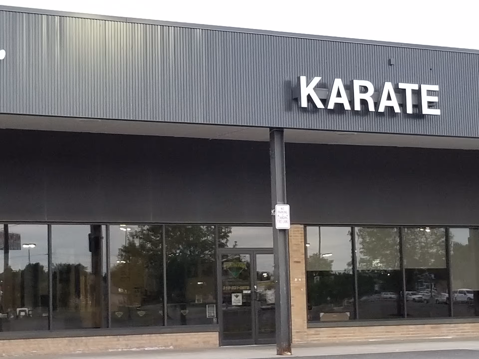 Front exterior of a building with large glass windows and a Karate sign.