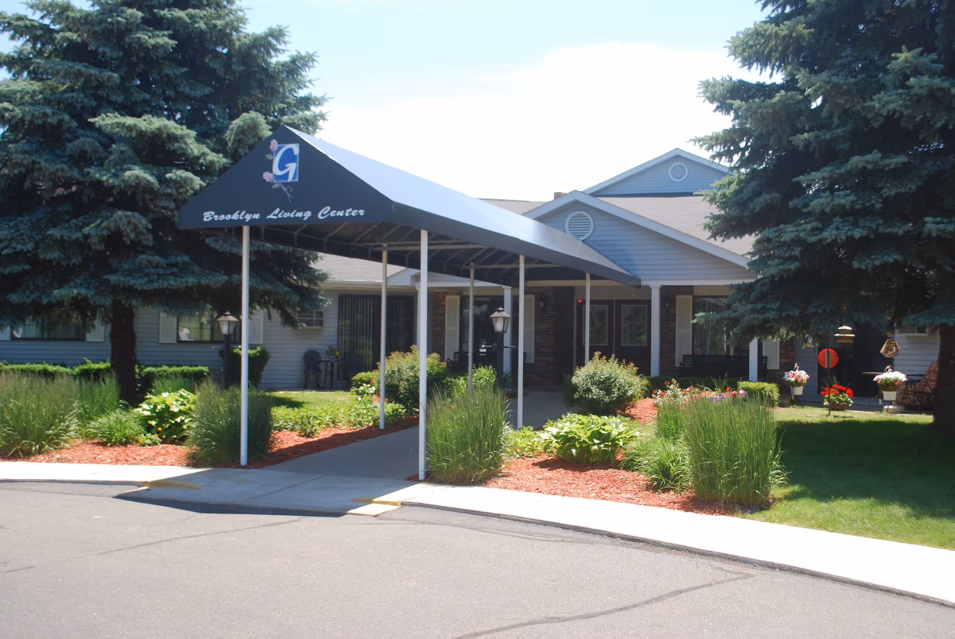 Front view of Brooklyn Living Center entrance with a covered sidewalk and landscaping.