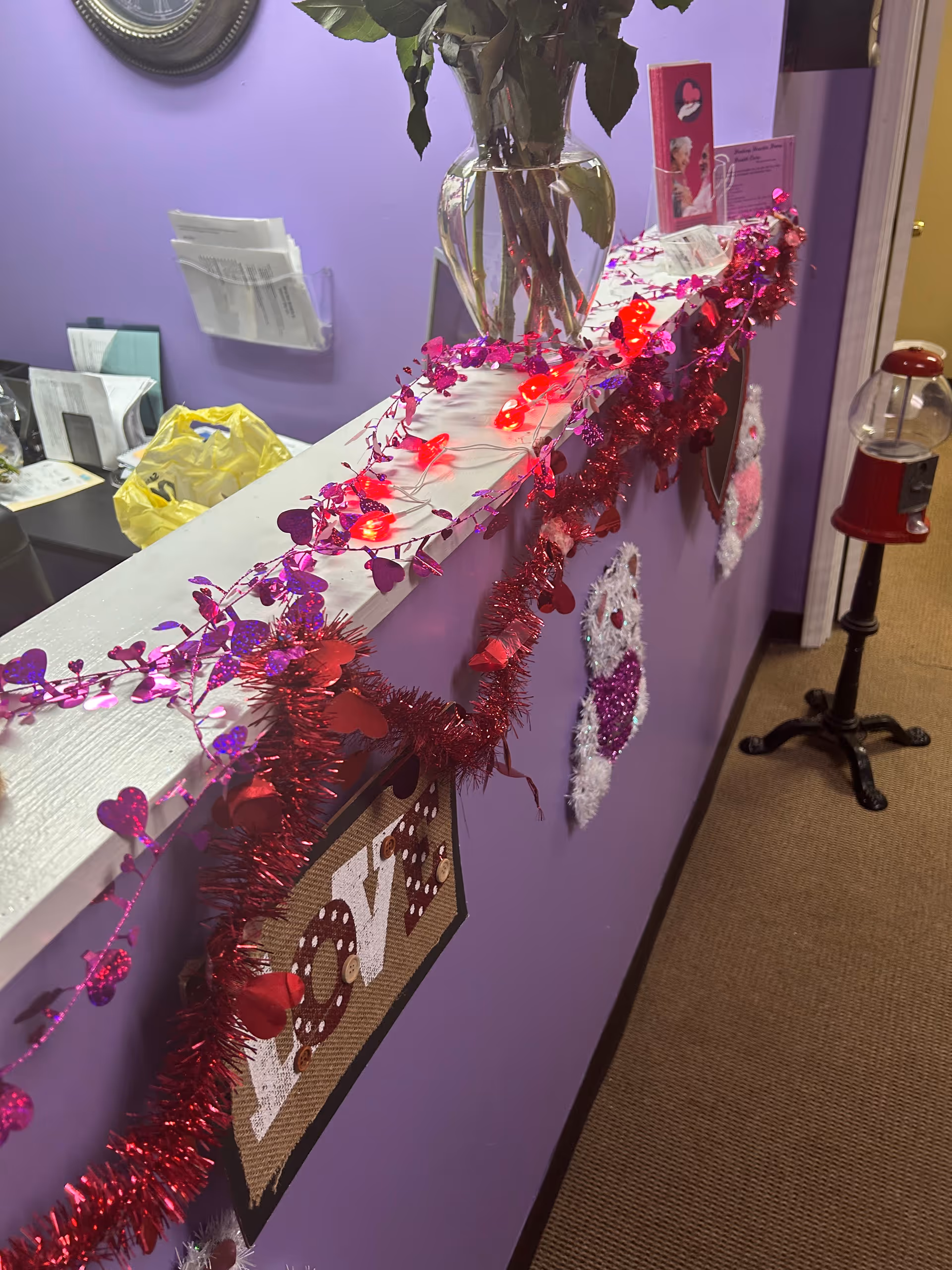 Purple hallway decorated with red-pink heart garlands and a vase.