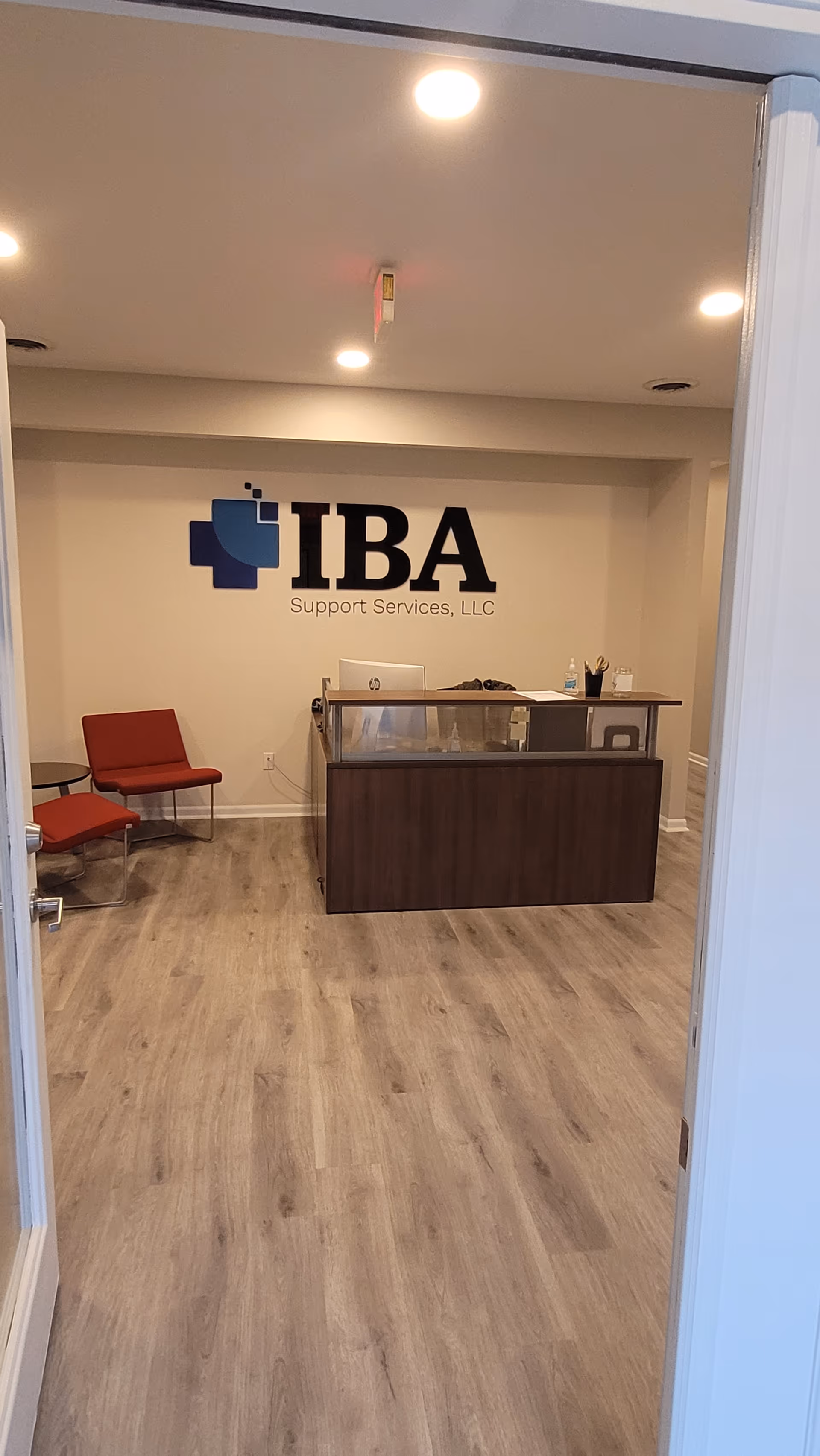 Reception area with a dark wood desk, red chairs, and IBA logo on the wall.