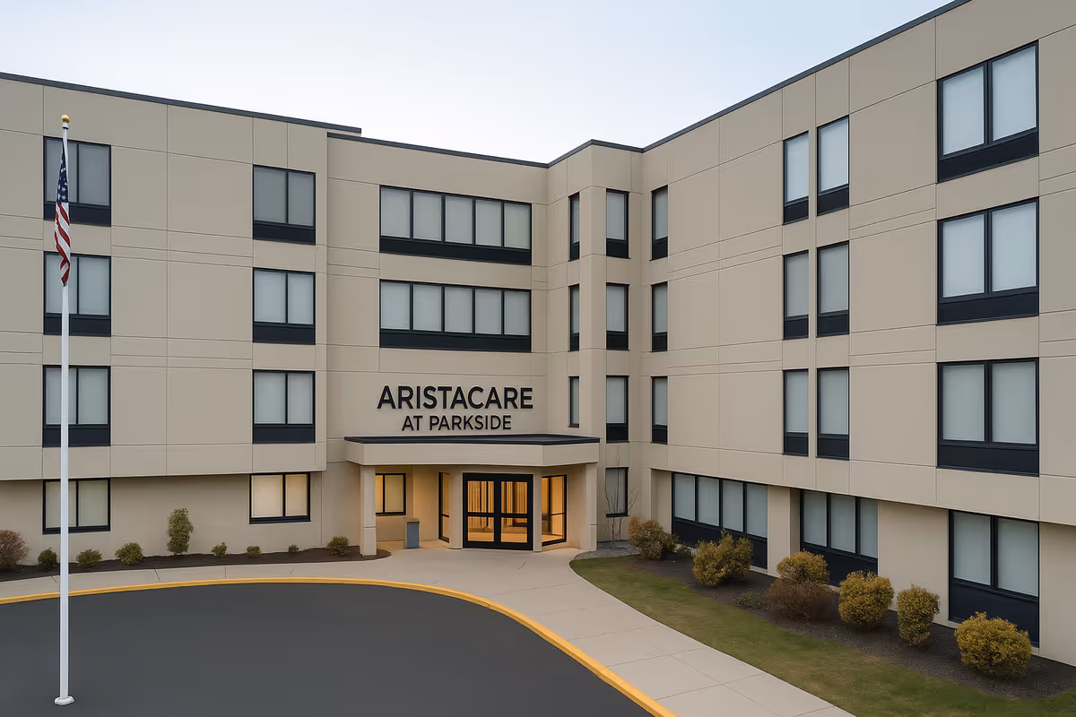 Exterior view of Aristacare at Parkside senior living building, entrance, flagpole, curved driveway.