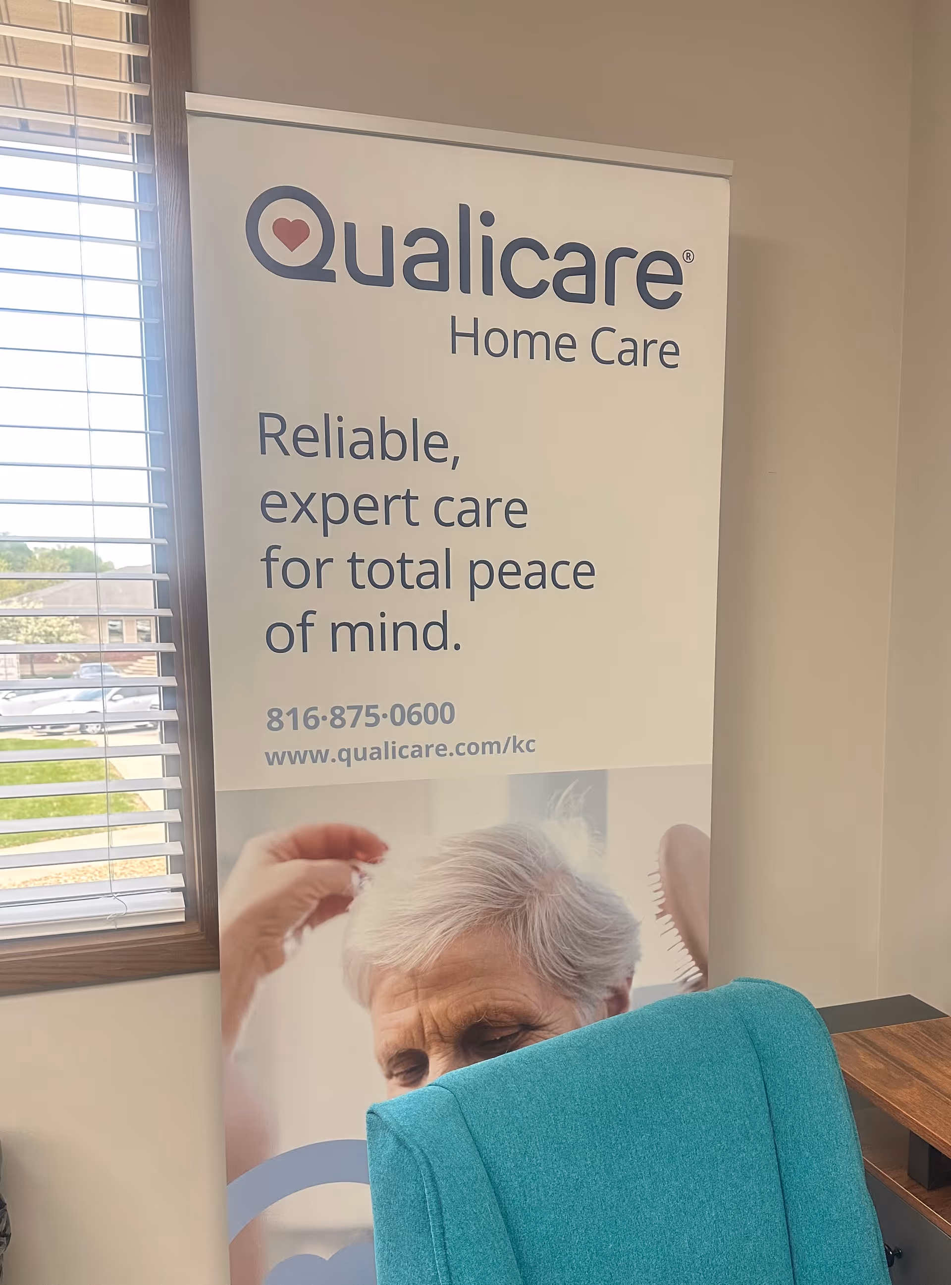 Indoor lobby with a Qualicare Home Care banner and teal chair