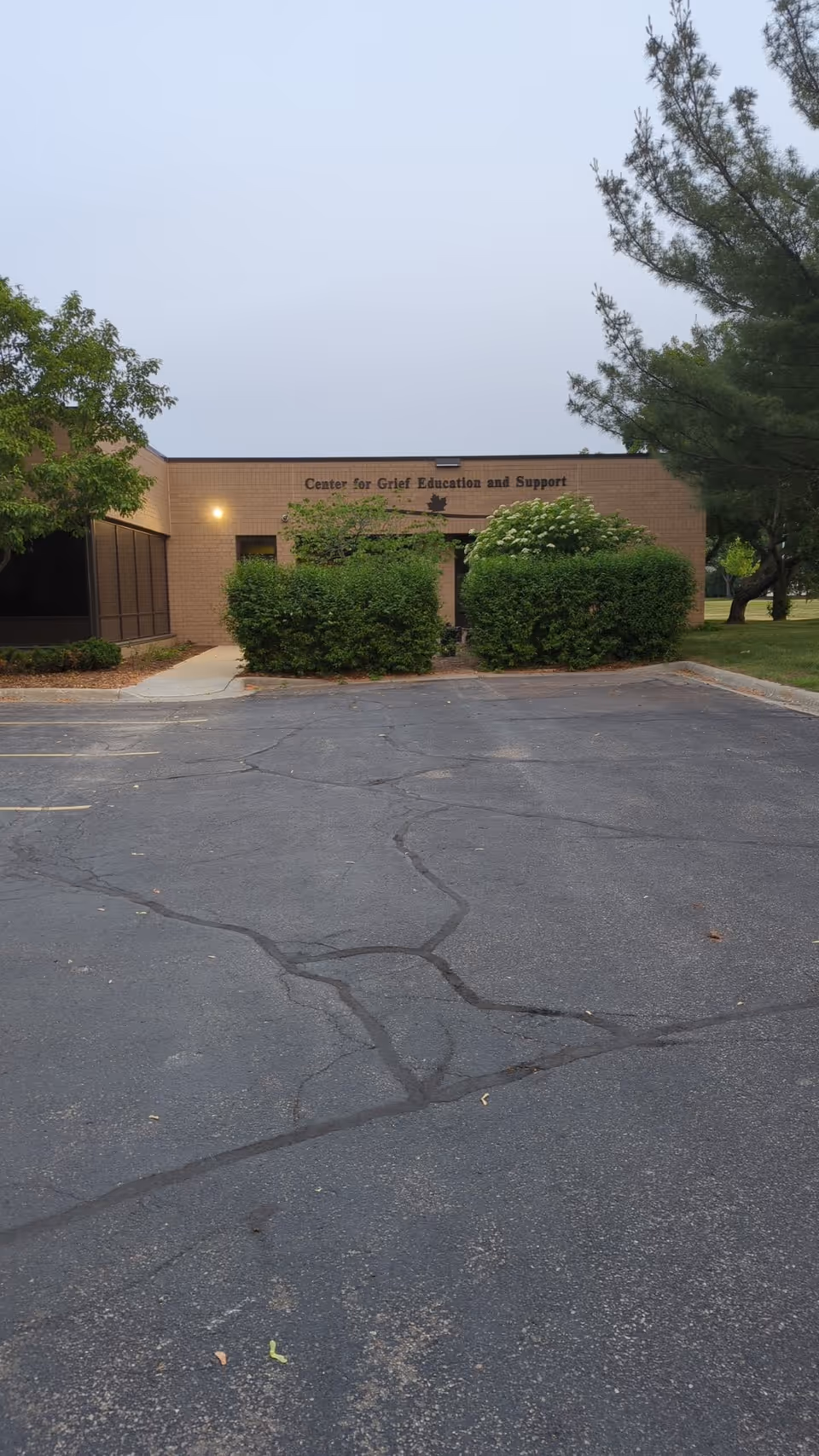 Exterior view of a brick building labeled Grief Education and Support with a parking lot.