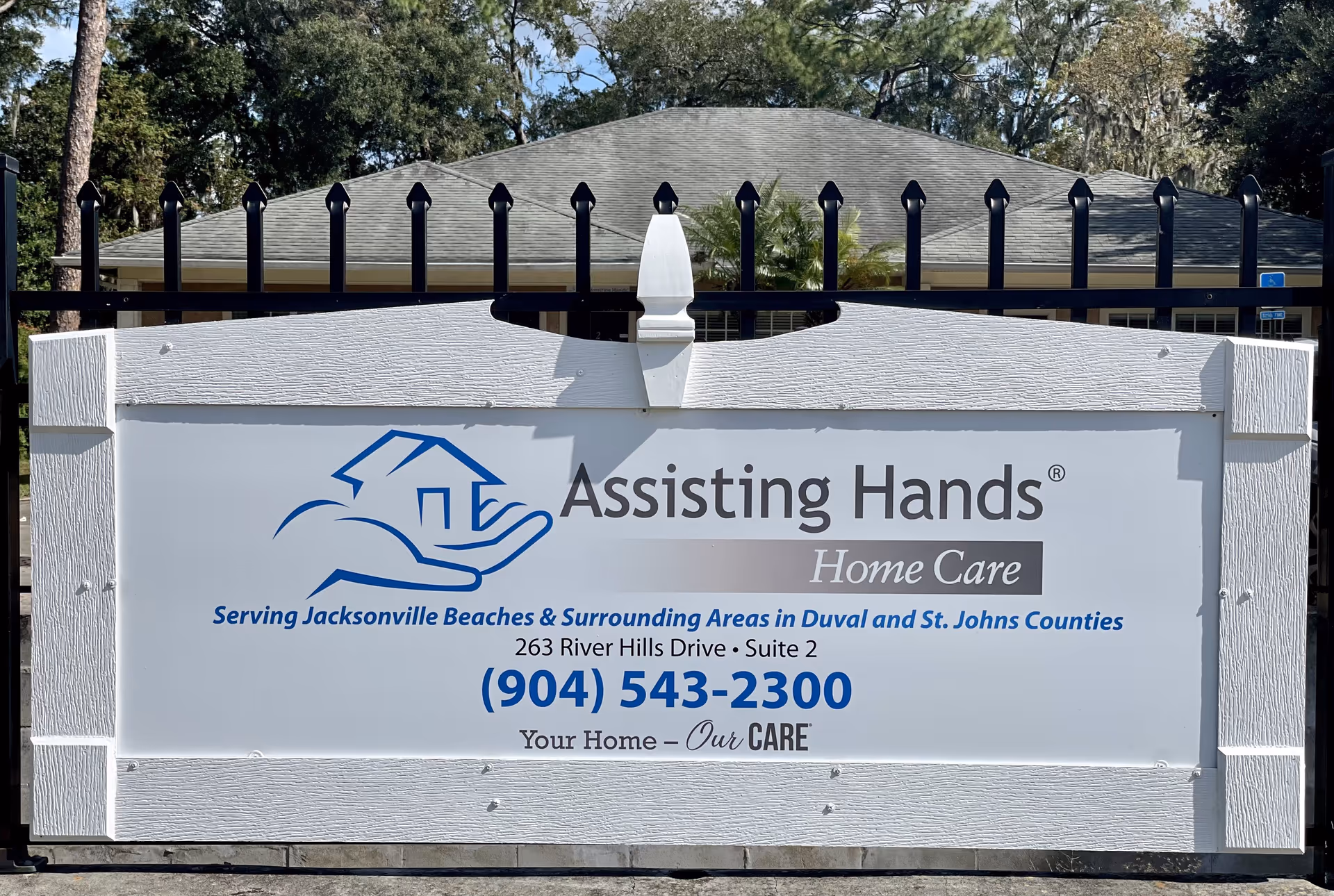 Exterior sign for Assisting Hands Home Care in front of a building.