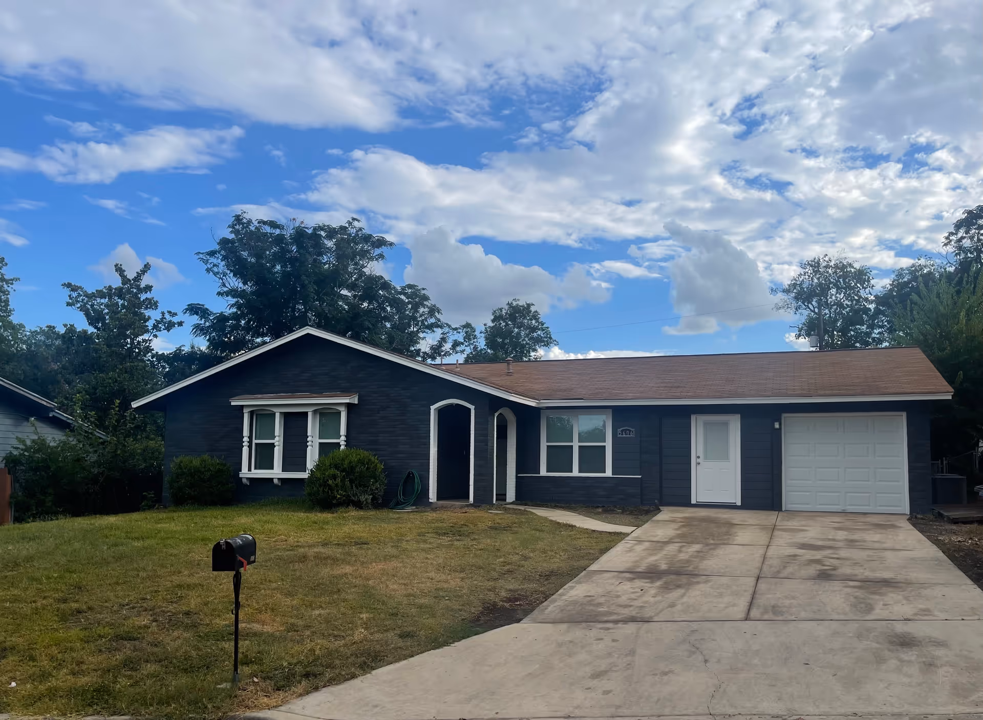 Blue single-story house with driveway, front lawn, and white garage door.