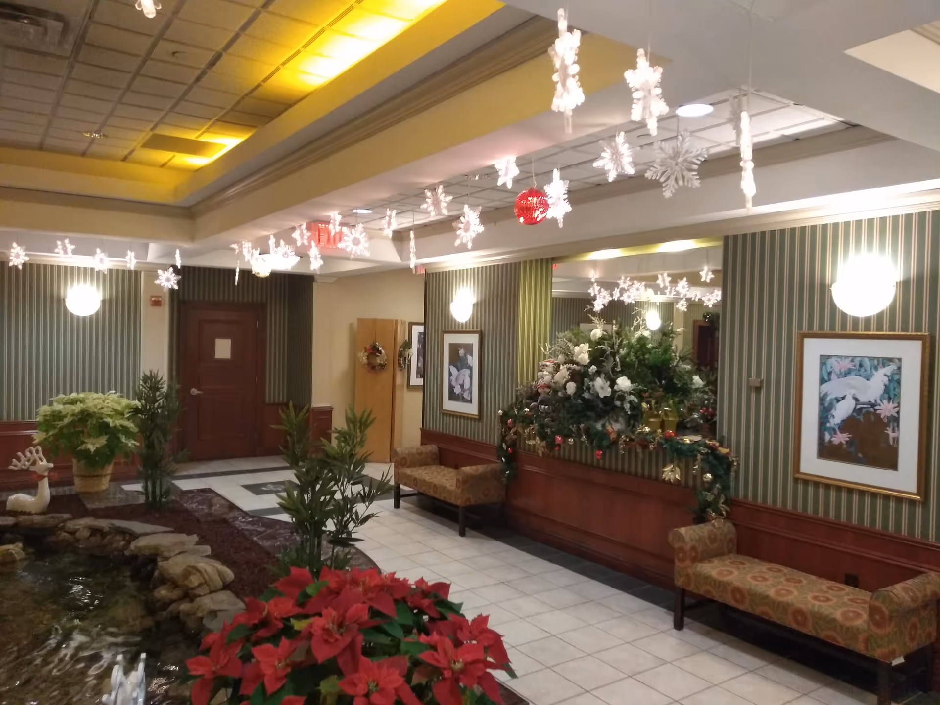 Indoor lobby at Regal Heights with holiday decor, plants, a water feature, and seating.