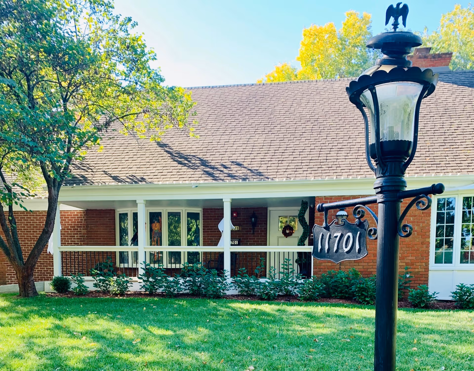 Brick memory care home with a covered front porch, manicured lawn, and decorative streetlamp.