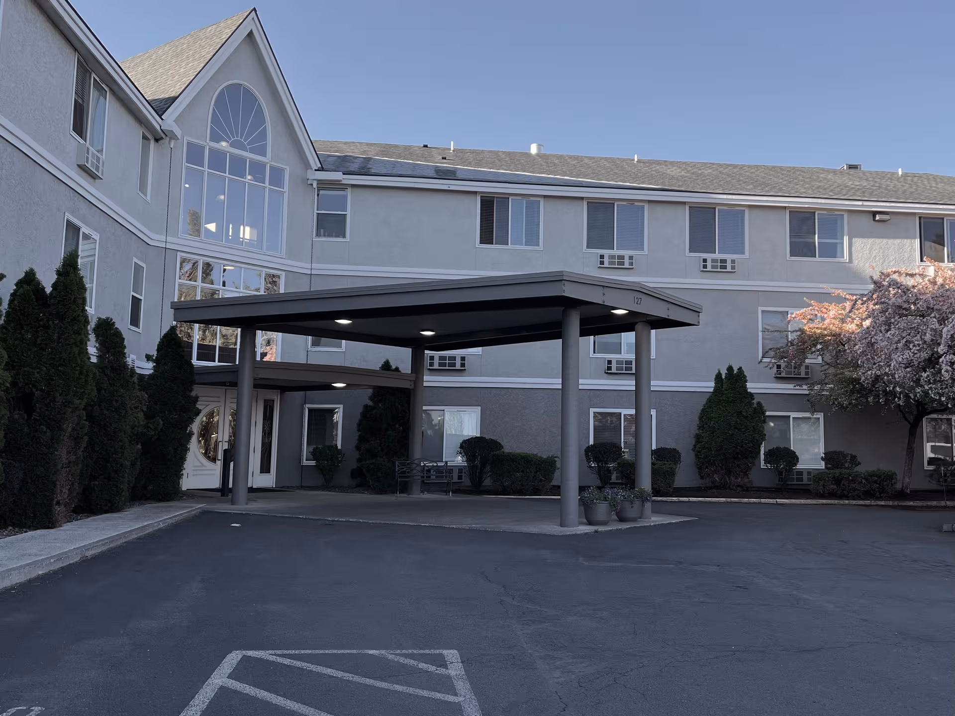 Exterior view of Regency Village at Bend with a covered entrance and landscaped driveway.