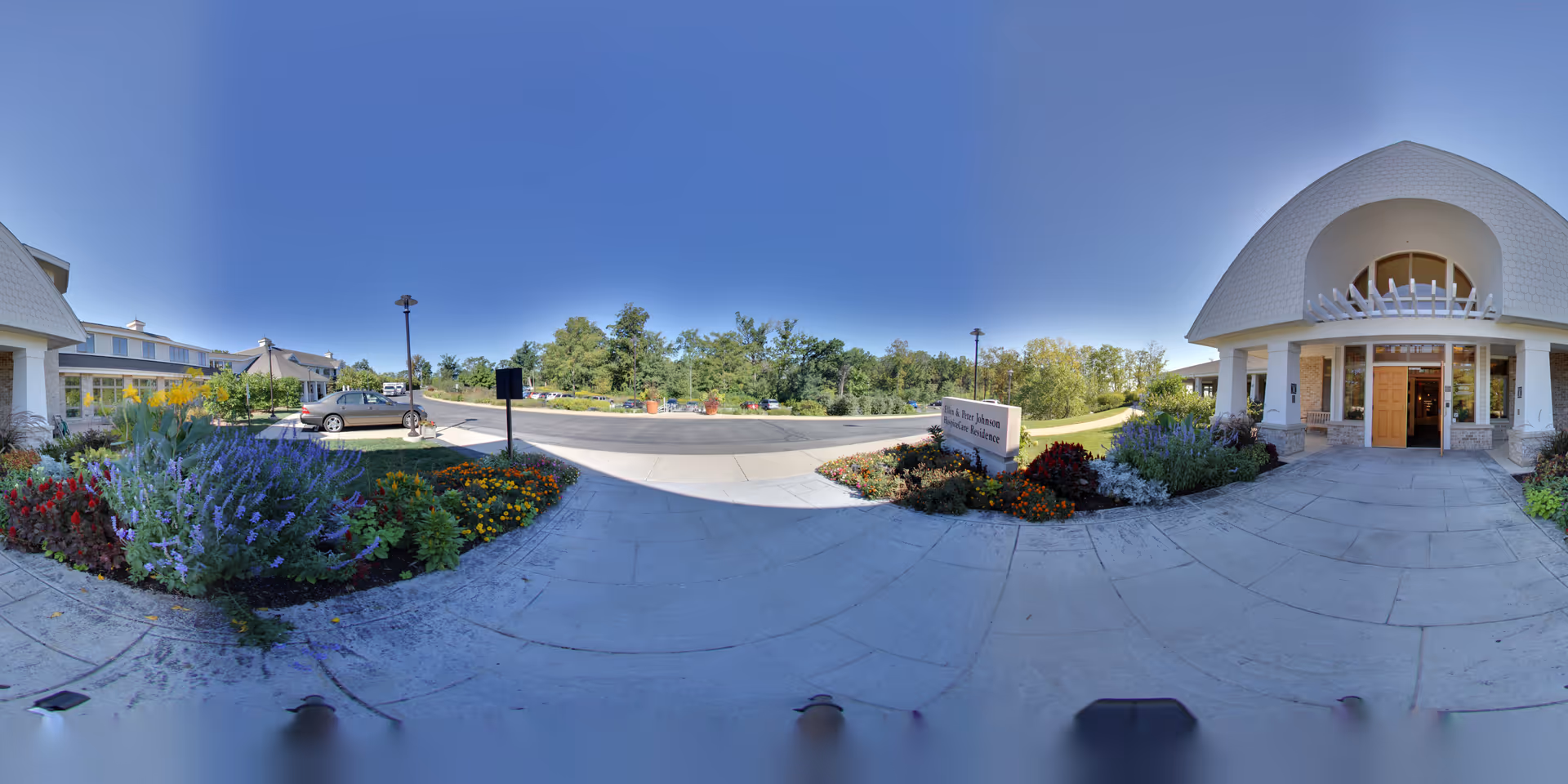 Front entrance of Agrace senior living facility with landscaped garden and blue sky.