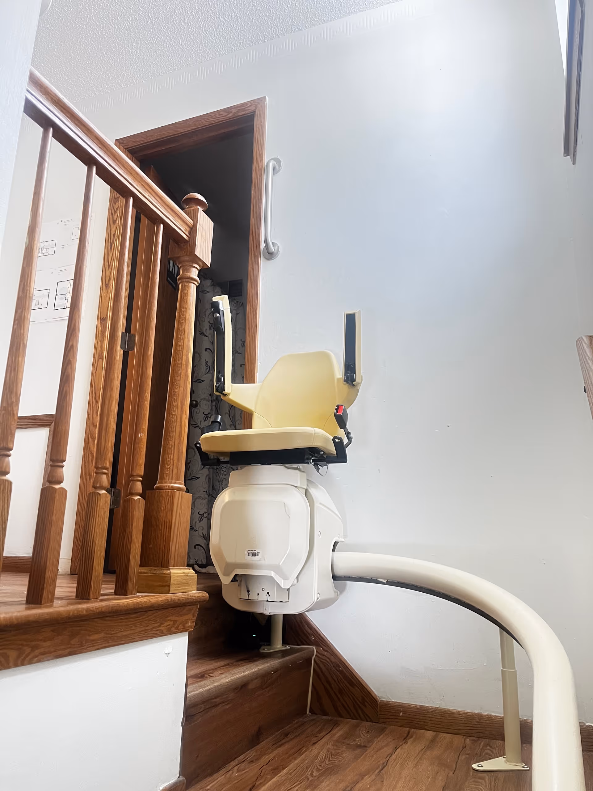 Indoor staircase with a beige stairlift chair mounted to the railing.