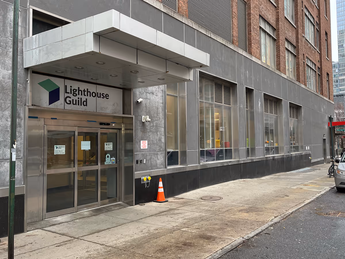 City sidewalk in front of a Lighthouse Guild building with glass entrance doors.