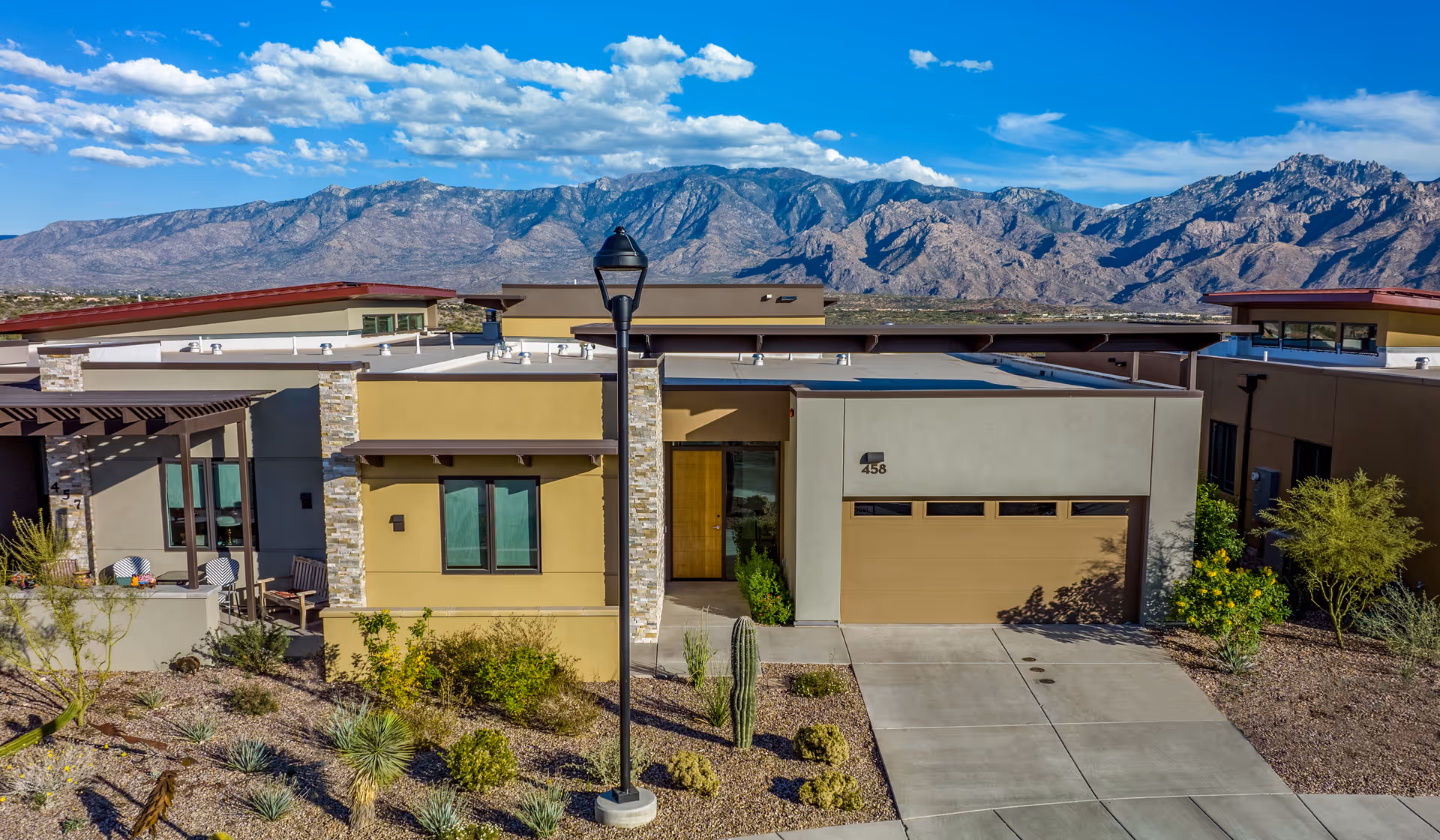 A modern, single-story facility with a two-car garage, desert landscaping, and distant mountains.