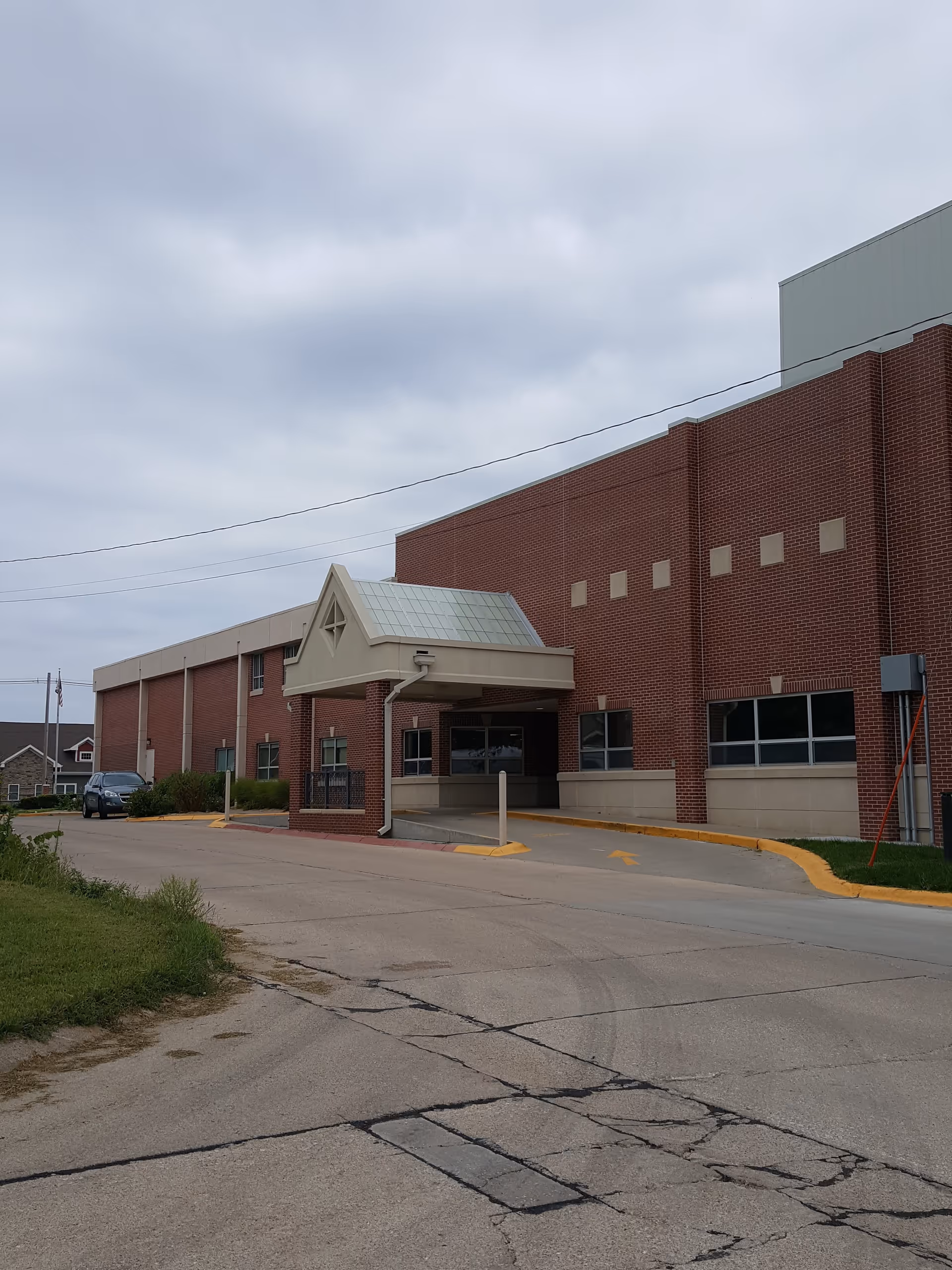 Brick medical facility exterior with a covered entrance and a wide driveway leading to the doors.