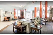 Bright senior living lobby with blue walls, red curtains, and comfortable seating.