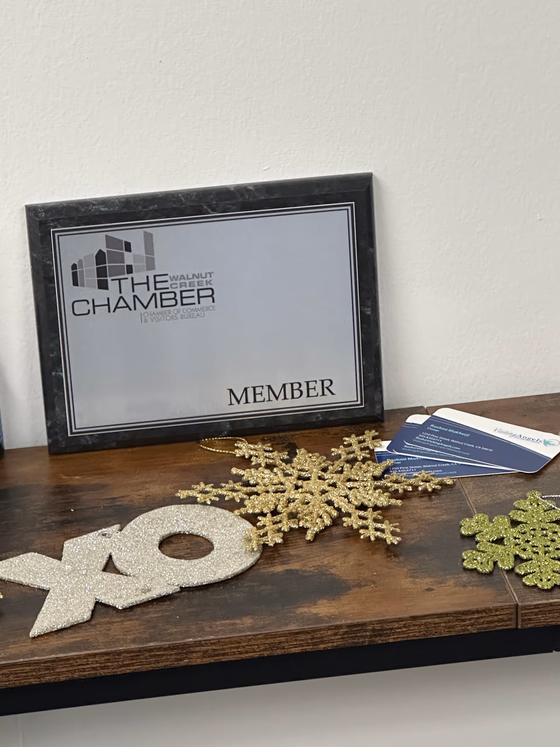 Framed sign reading 'The Chamber' on a wooden table with glittery snowflake decorations.