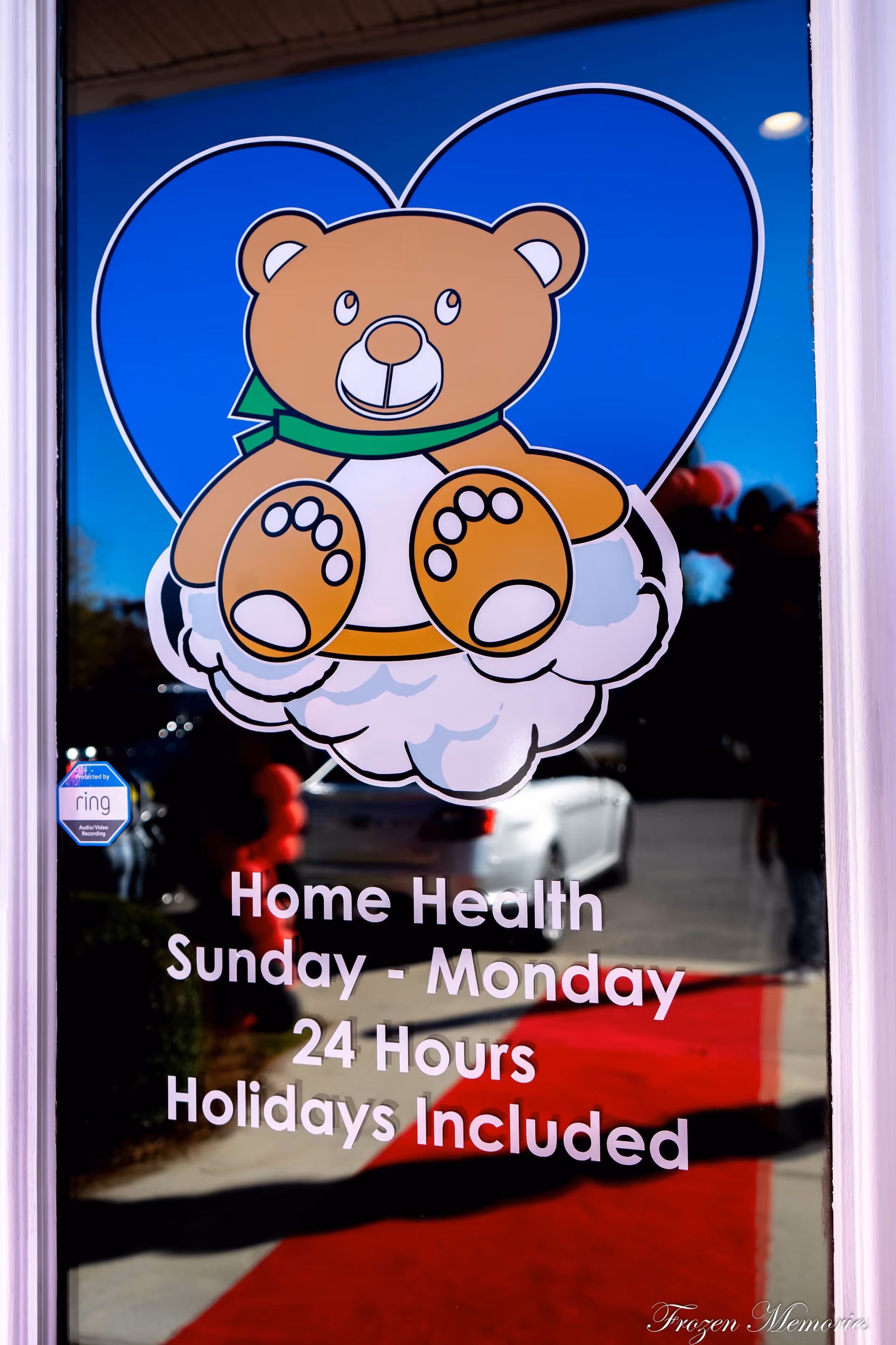 Glass door with a large teddy bear graphic and Home Health promotional text Sunday-Monday