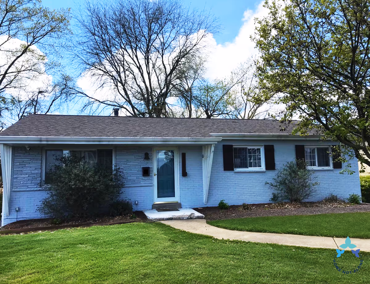 Blue single-story home with front entrance, windows, and well-kept green lawn.